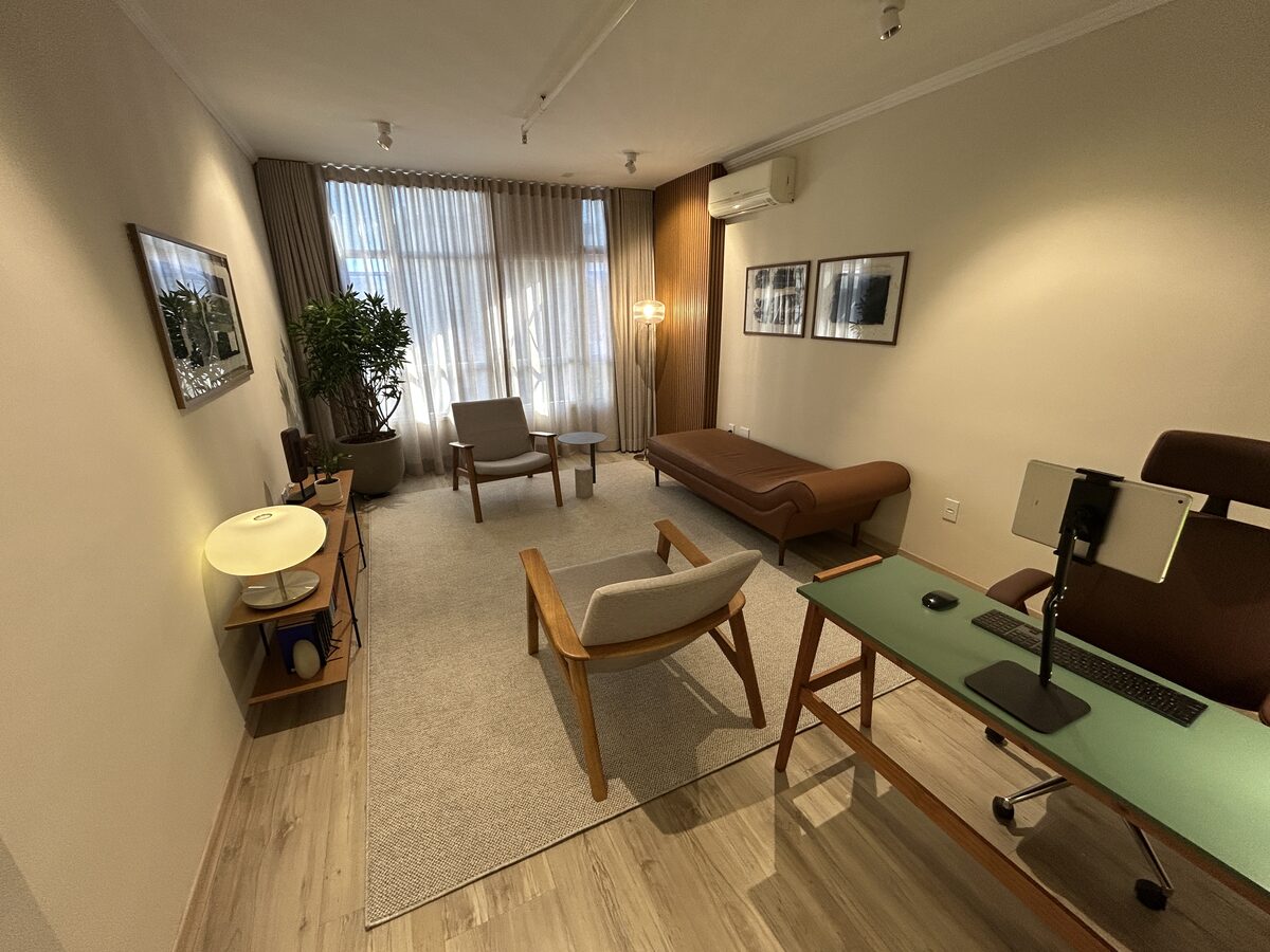 Vista geral da sala do consultório de psicologia em Pinheiros, com poltronas e divã